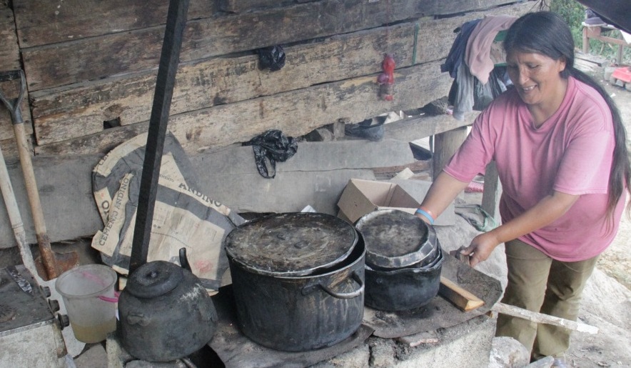 Augusta Flor, clienta de la Fundación Microfinanzas BBVA, cocinando en su cocina de barro. Fotografía de Augusta Flor, una historia de éxito de la Fundación Microfinanzas BBVA.