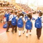 Fotografía de niños caminando con morrales donados por BBVA con elementos escolares