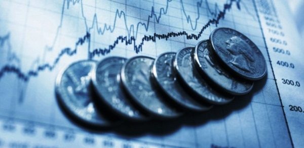 Monedas sobre hoja con gráfica del comportamiento de la economía Fotografía de Monedas sobre hoja con gráfica del comportamiento de la economía