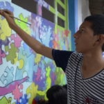 Fotografía de Estudiante de la Rafael Uribe Uribe pintando un mural de rompecabezas