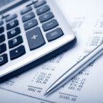 Fotografía de Impuestos en la reforma tributaria, calculadora sobre facturas y esféro