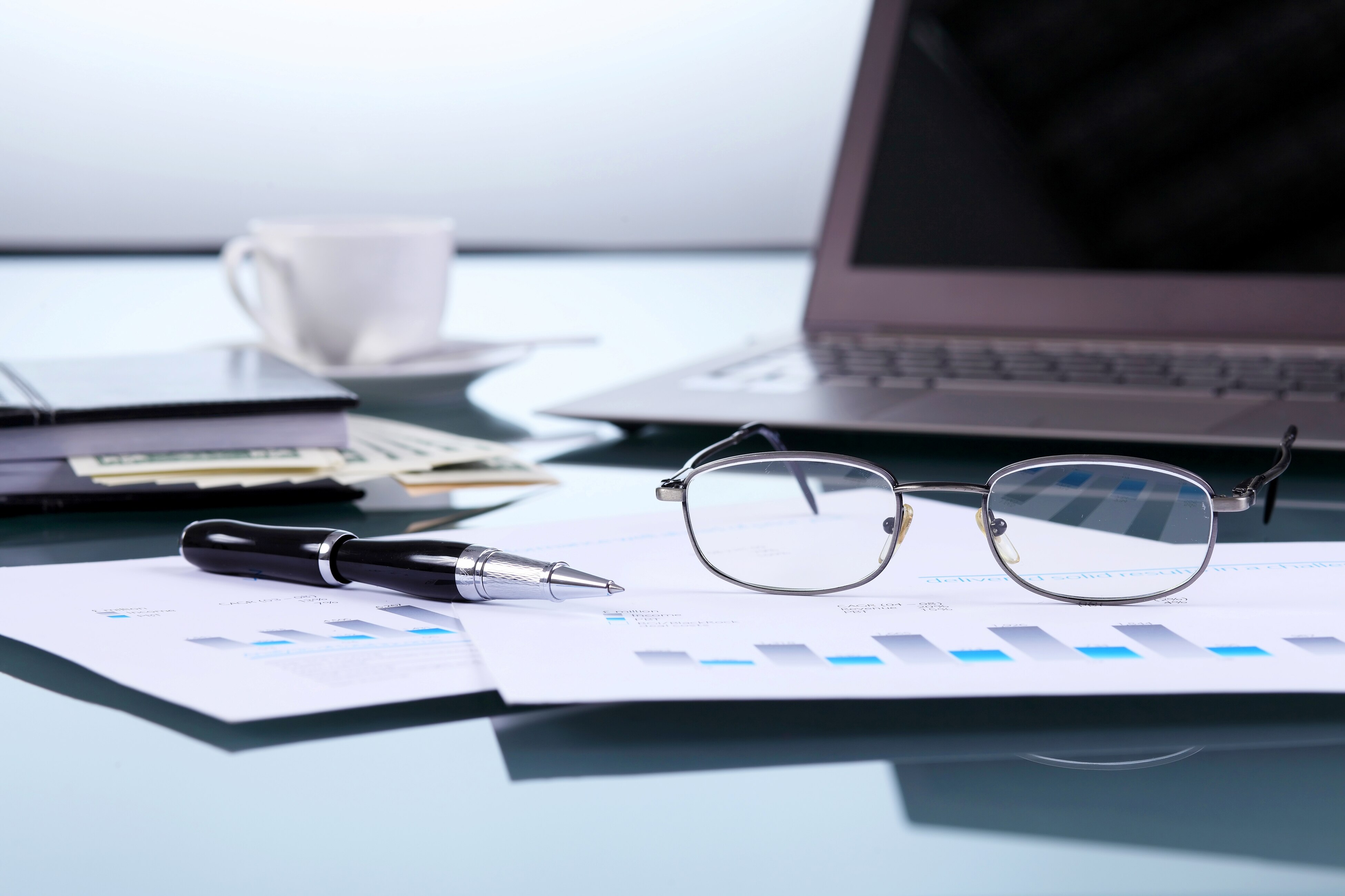 Computador junto a gafas e informes financieros Fotografía de Computador junto a gafas e informes financieros