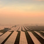 Fotografía de paneles solares y molinos de viento para ilustrar un artículo sobre financiación verde en BBVA