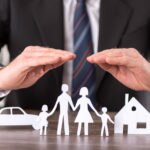 Concept of insurance with hands over a house, a car and a family Concept of insurance