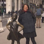 Fotografía de Jessica, emprendedora de la FMBBVA, posa junto a La Niña sin miedo en Wall Street NY