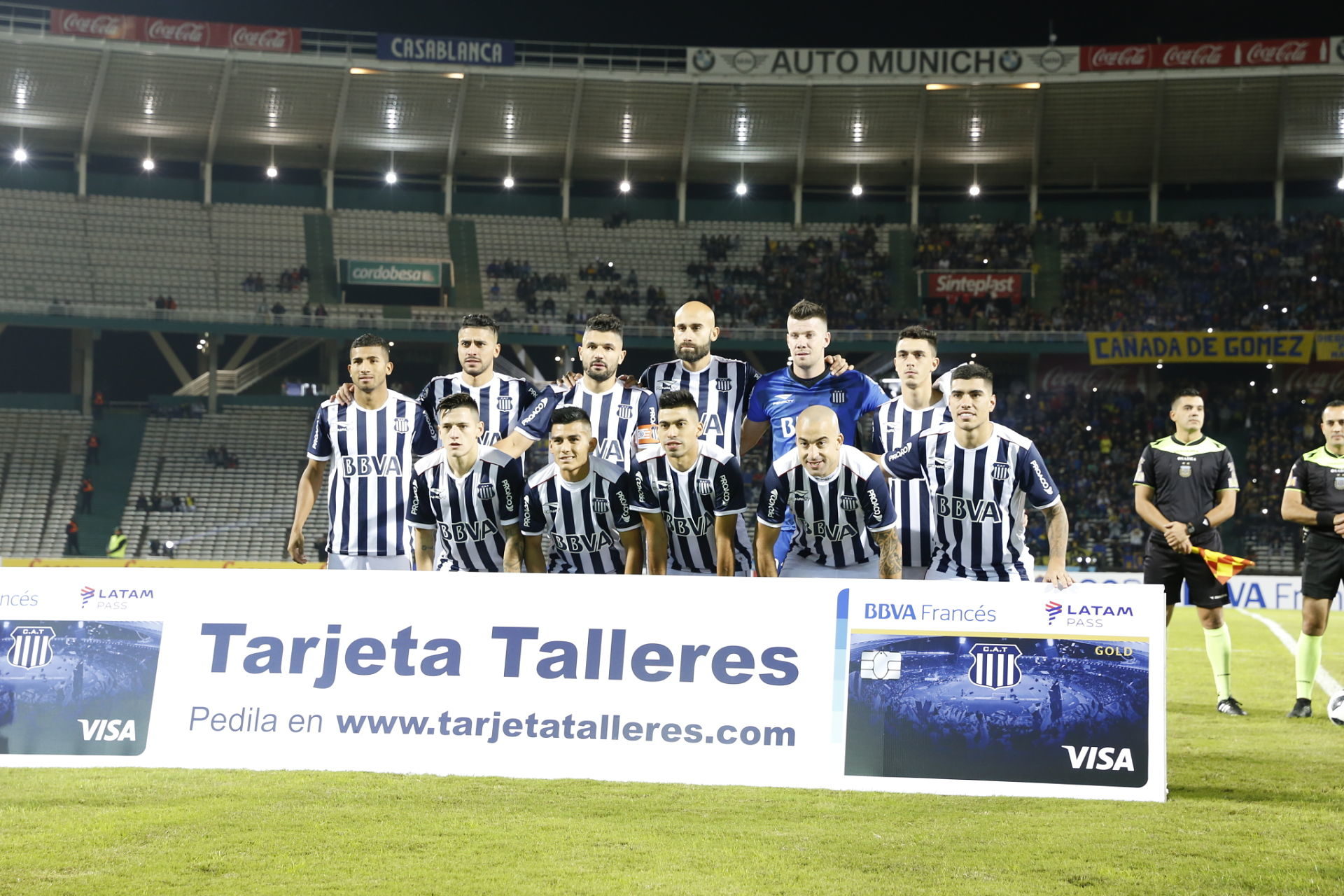 El equipo de Talleres posa frente al cartel de Tarjeta Talleres