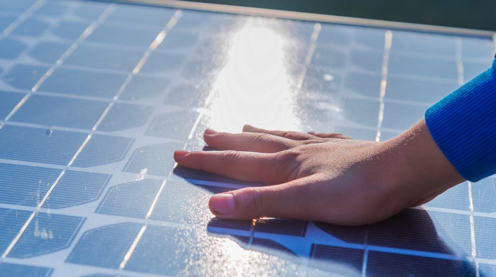Hand of the boy touching Solar cell in day light. Human hand touching a solar panel