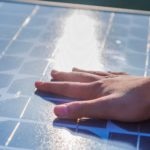 Hand of the boy touching Solar cell in day light. Human hand touching a solar panel