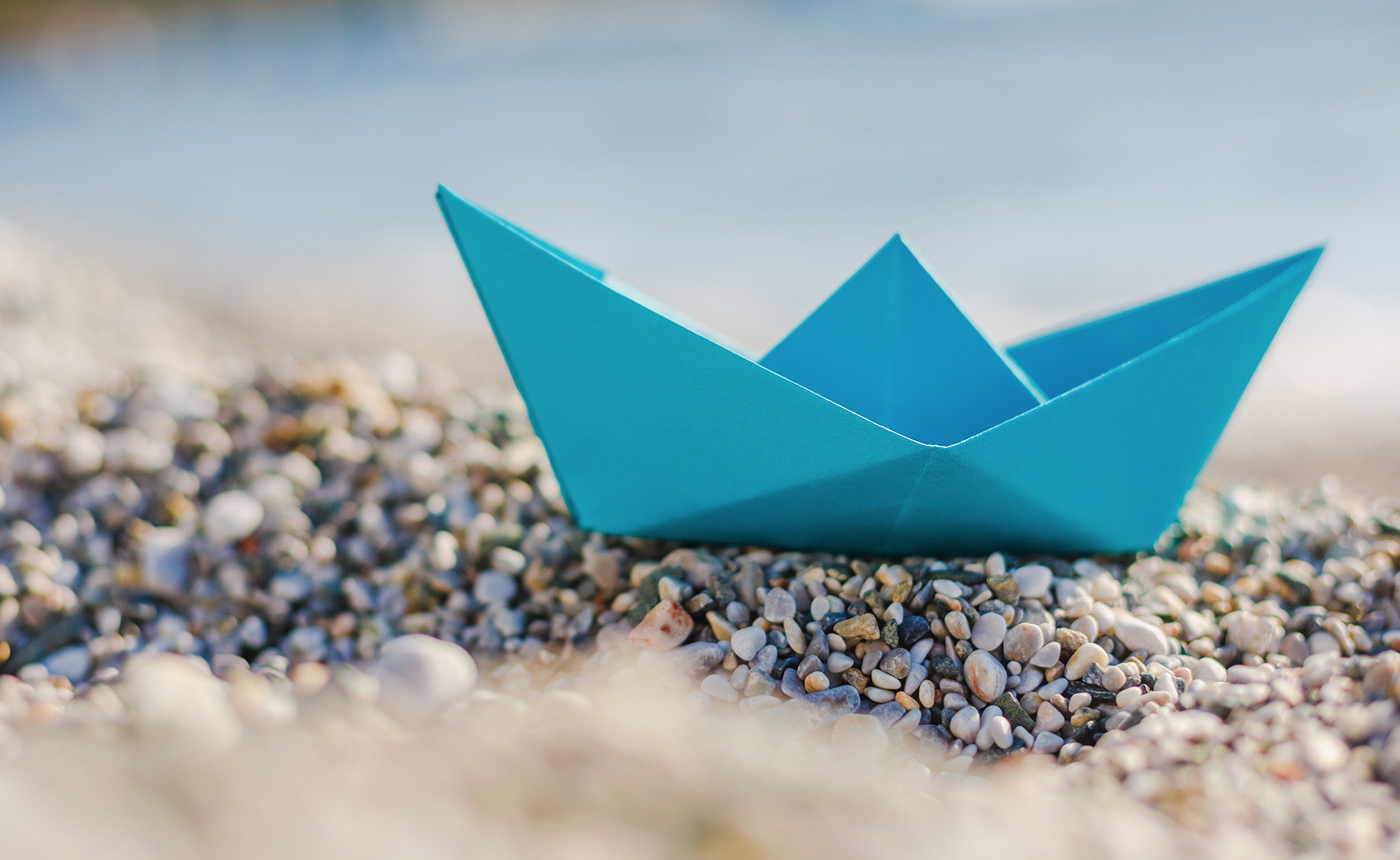 Fotografía de Barco, papel, playa, piedras, BBVA, sostenible, orilla, azul