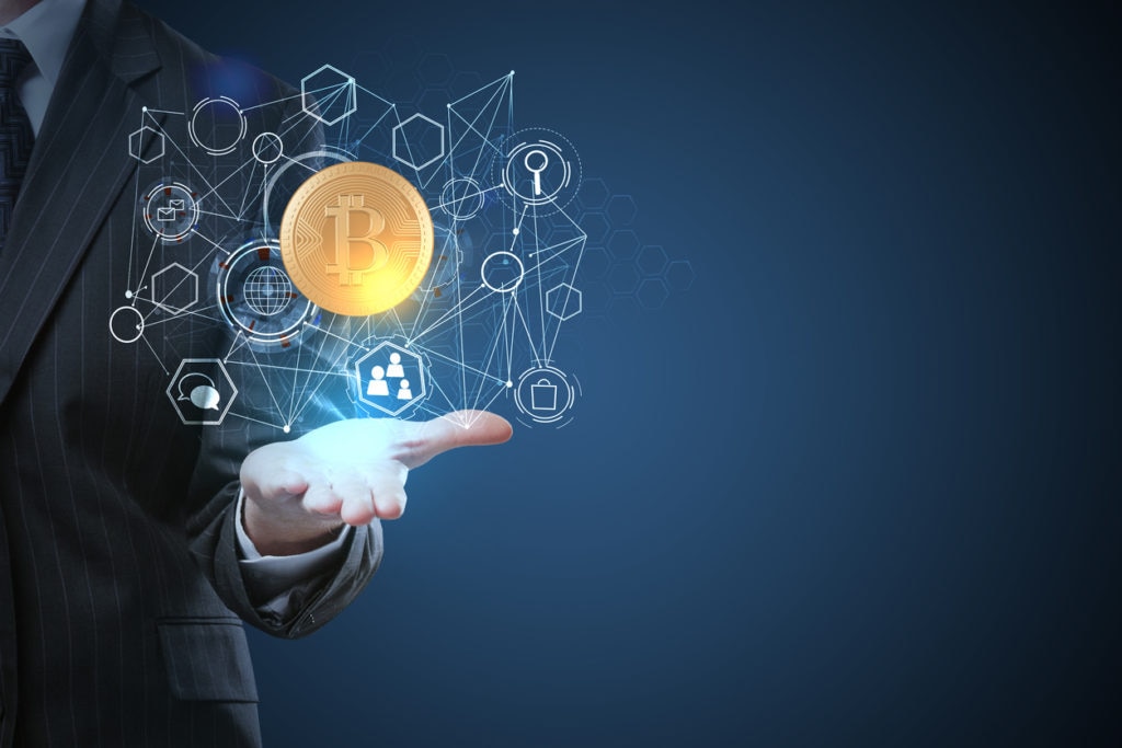 Businessman holding abstract digital bitcoin hologram on blue background. Innovation and cryptocurrency concept Businessman holding abstract digital bitcoin hologram on blue background. Innovation and cryptocurrency concept