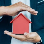 Business man hand hold the house model saving small house. seguro multiriesgo