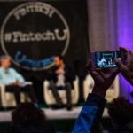 A photo of an attendee taking a picture of panelists at Fintech University.