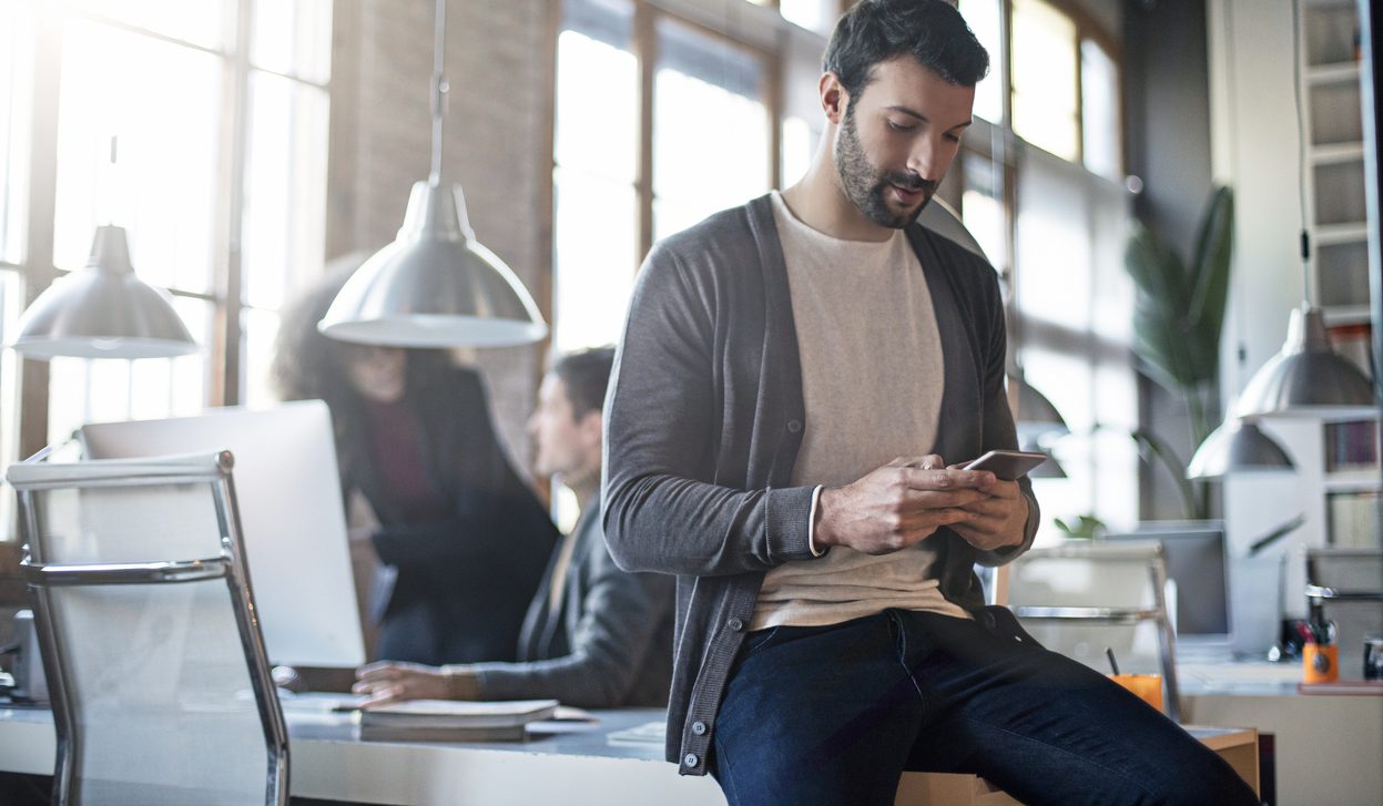 RESOURCE recurso mobile work job Businessman checking the mobile phone sitting on his desk